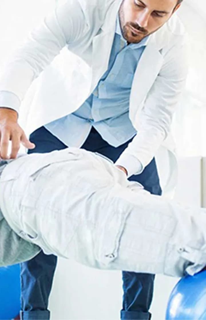 Physiotherapist examining a patient's lower back at Dr. Biswas Pain Clinic in Agartala
